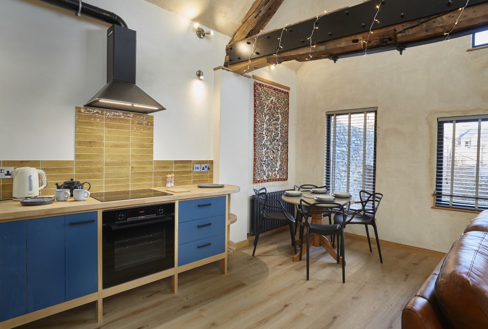 A view from the kitchen towards the dining area where 4 guests can sit around the table