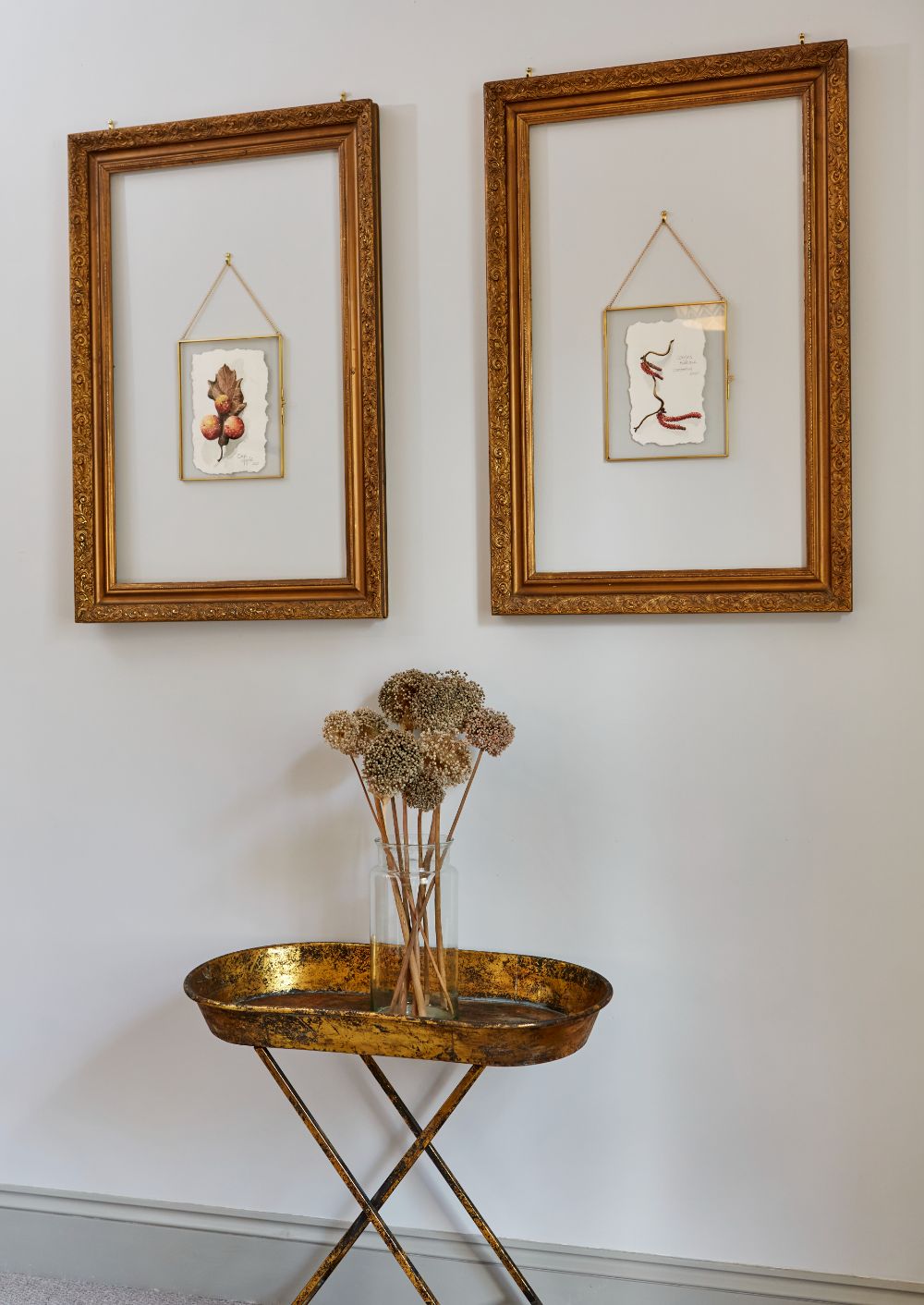 Botanical pictures adorning the wall, with dried flowers in a vase beneath