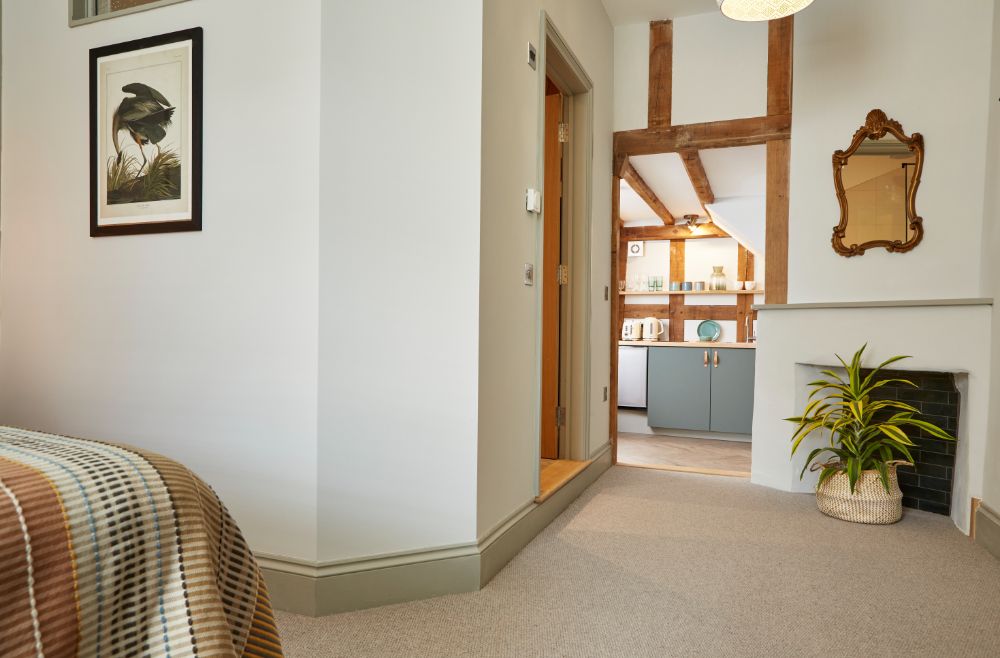 A view past the end of the bed to the oak-framed kitchenette