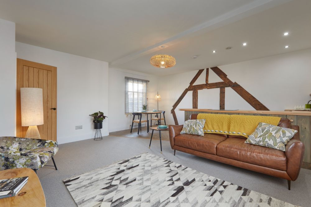 A view from the corner of the living room to the beautiful oak beams on the wall behind the kitchen and dining area